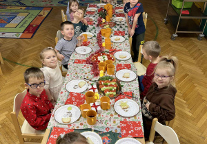 Na zdjęciu dzieci siedzą przy przystrojonym stole, dzieci jedzą wspólnie śniadanie mikołajkowe