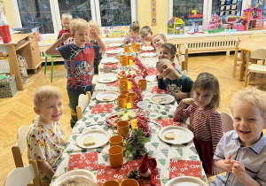 Na zdjęciu dzieci siedzą przy przystrojonym stole, dzieci jedzą wspólnie śniadanie mikołajkowe