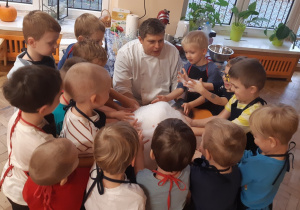 Chłopcy ustawieni wokół pomarańczowego stolika dotykają piany utworzonej z wody, suchego lodu i płynu do naczyń.