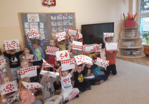 Dzieci pozują do zdjęcia trzymając w rękach białe kartki, na których ponaklejane są czerwone serduszka otrzymane od rówieśników.