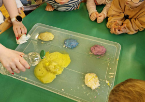 Na zdjęciu dzieci obserwują jak nauczyciel wywołuje reakcję powodującą wybuch wulkanu