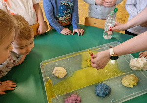 Na zdjęciu dzieci obserwują jak nauczyciel wywołuje reakcję powodujący wybuch wulkanu