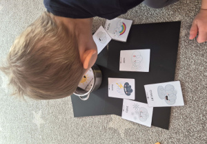 Na zdjeciu chłopczyk wkładający do garnka symbole pogodowe