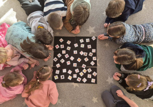 Na zdjęciu dzieci leżą i oglądają symbole pogodowe położona na czarnym kartonie