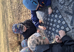 Na zdjęciu dzieci na spacerze w parku, dzieci grają w szachy