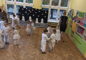 Zdjęcie tańca podczas przedstawienia choinkowego - dzieci ustawione w parach