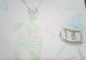 Na zdjęciu rysunek Jasia z grupy fioletowej o tematyce kosmicznej, na rysunku zielony kosmita obok narysowany statek kosmiczny