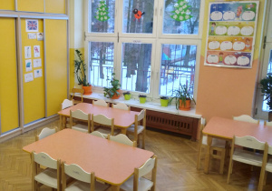 Na zdjęciu grupa zielona, na fotografii widać stoły przy, których na co dzień pracują dzieci z lewej strony znajduję się duża żółta szafa na wprost są okna